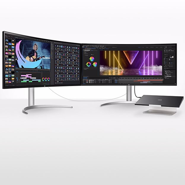 Zwei gebogene Monitore auf einem Schreibtisch, verbunden mit einem Laptop, zeigen Videobearbeitungssoftware und farbenfrohe Visuals für Multitasking.