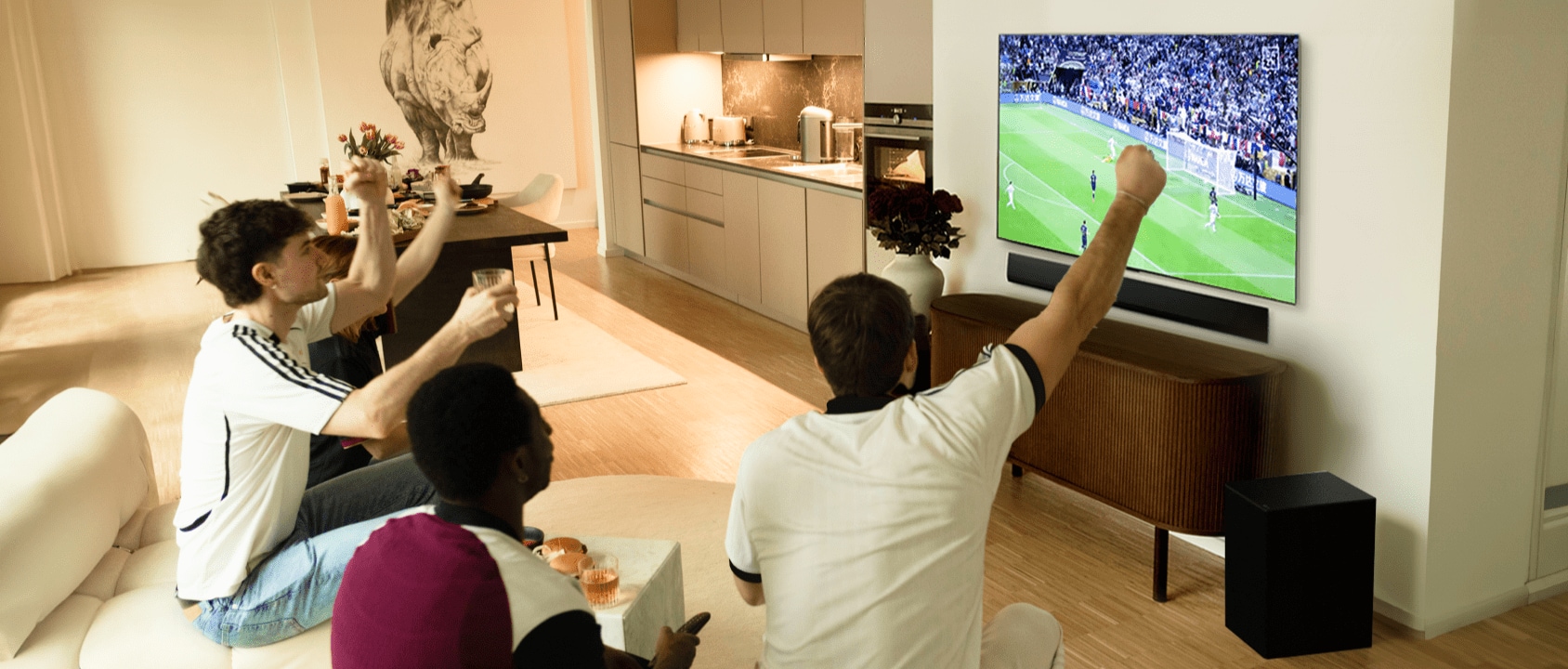 Janis Danner grüßt, als sie mit ihren Freunden auf dem Sofa sitzt und ein Fußballspiel auf ihrem LG OLED G4 TV sieht.