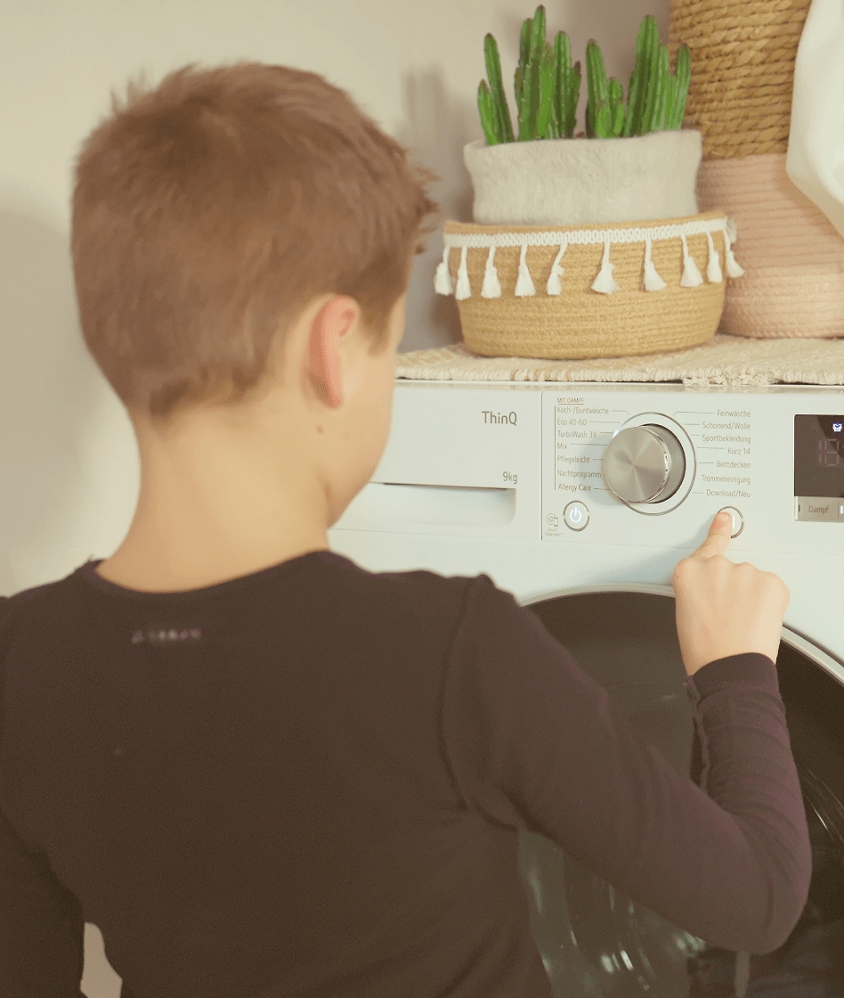 Sohn bedient die Waschmaschine