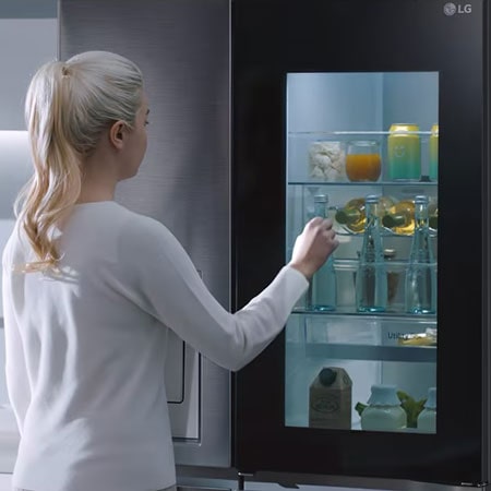 Eine Person holt sich Wasser aus dem Kühlschrankspender in einer Tasse
