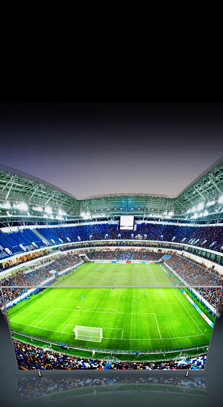 Ein sehr weiter Blick auf das Fußballstadion ist zu sehen und ein Teil des Bildes wird auf einem QNED TV angezeigt.
