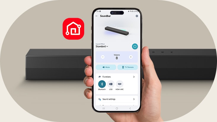 En hånd holder en smartphone, der viser LG ThinQ-appen. Ved siden af vises et LG ThinQ-appikon. En SH5A Soundbar er anbragt bagved.