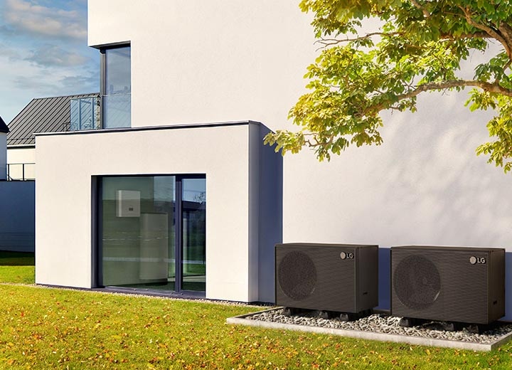 En installatør forklarer opvarmningsløsningen til et par, der står foran en LG Therma V-varmepumpe, som er anbragt udenpå et hus.