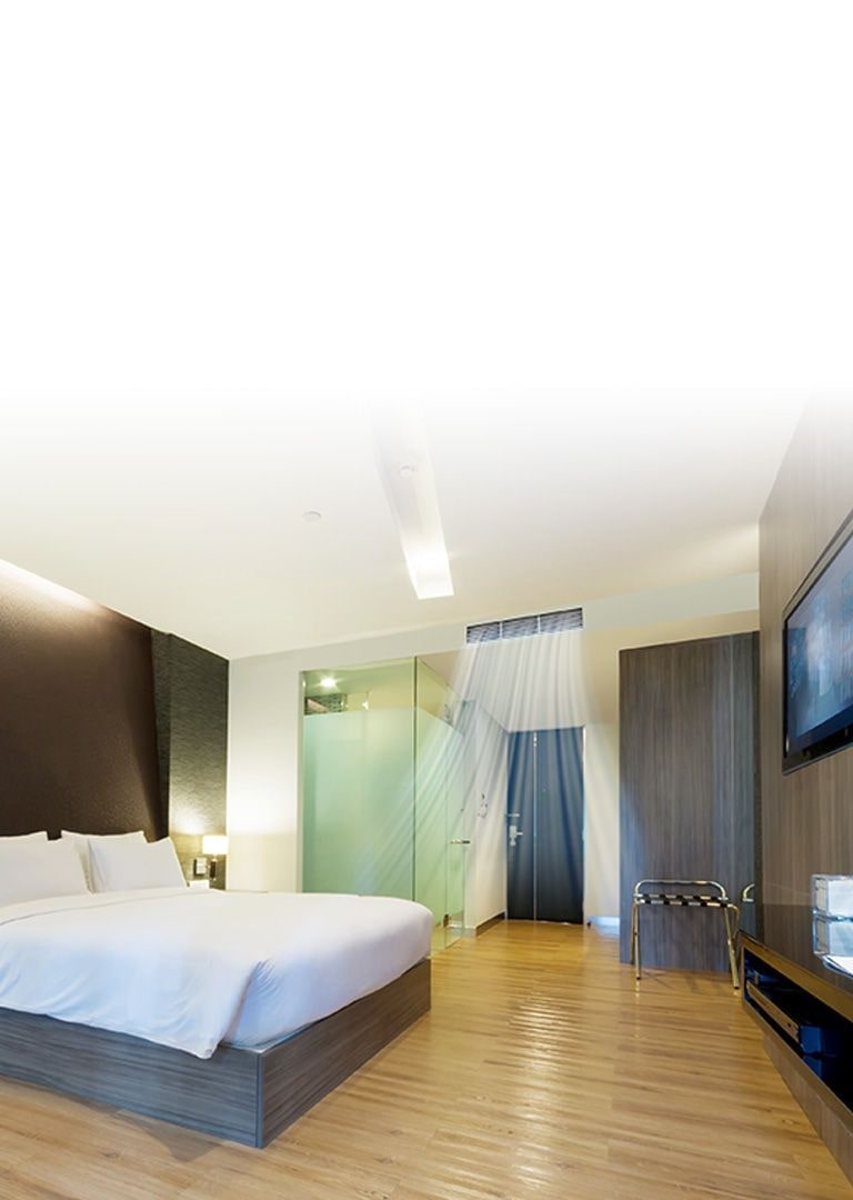 En ceiling concealed duct leverer blå luftstrømme i et hotelværelse med vægge i brune toner og en queen-size seng dækket af hvidt sengetøj.