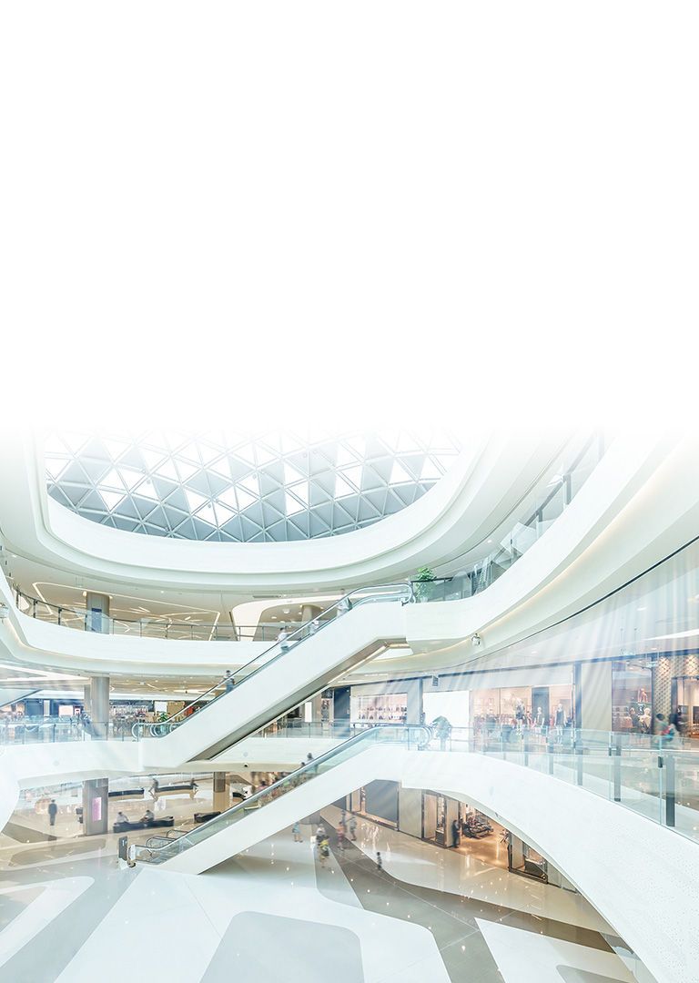 Ceiling concealed ducts leverer blå luftstrømme i en stor atriumbygning med tre etager og flere indendørsbutikker og lange rulletrapper.