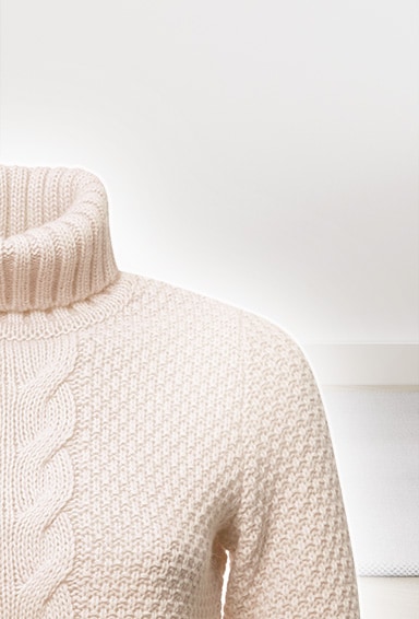 En sweater vises med en linje, som går ned gennem midten. Venstre side er mærket med “Almindelig varme-/gastørretumbler”, mens højre side er mærket med “LG DUAL Inverter Heat Pump-tørretumbler”. Sweateren til venstre krymper, mens sweateren til højre bevarer formen og forbliver blød.