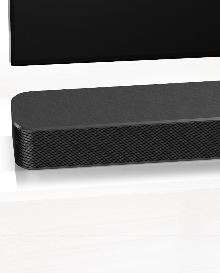 TV på væggen, LG soundbar nedenunder på en hvid marmorhylde med en subwoofer til højre. TV, der viser et par i en bil.