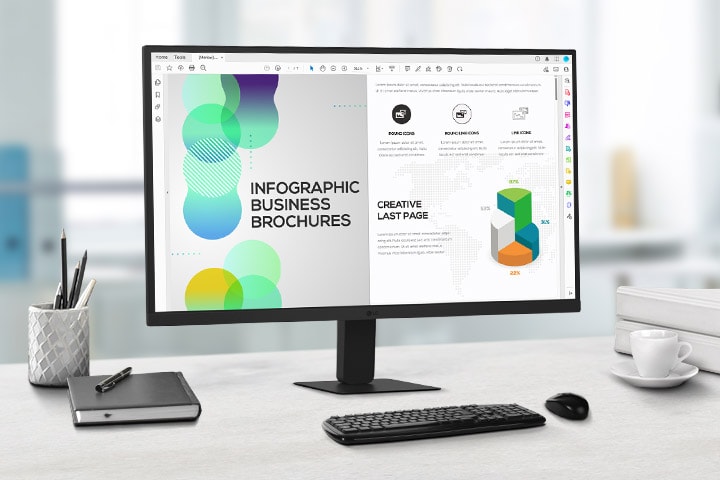 På skrivebordet står der en IPS-skærm i QHD, som viser arbejde med dokumenter. Ved siden af skærmen er der en kuglepensholder, en dagbog, en kuglepen, et tastatur, en mus og et krus.