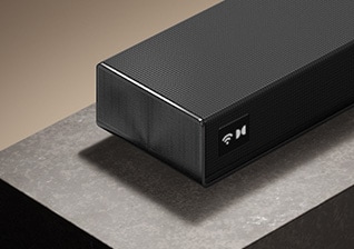Vinklet visning af LG Sound Suite H7 anbragt på en bordplade, hvor ses dens slanke matsorte kabinet og førsteklasses design.