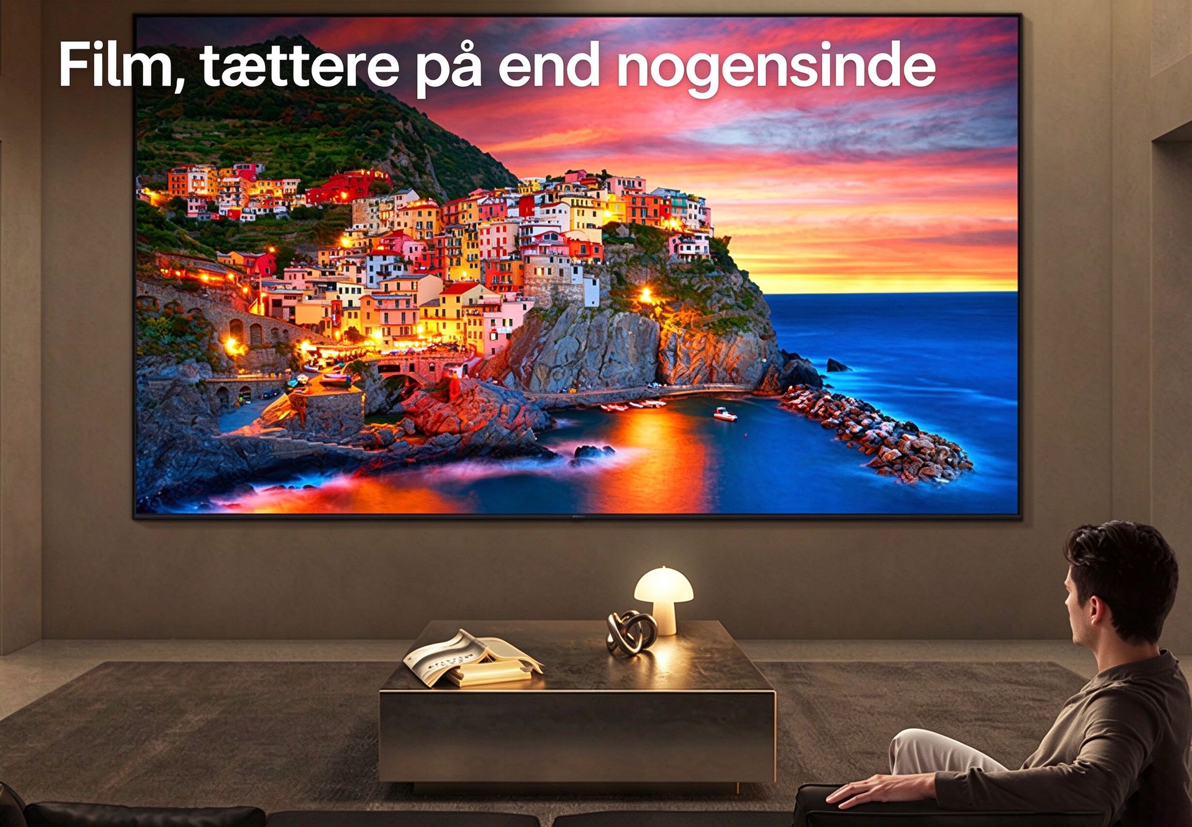 LG Ultra Big TV er vægmonteret i en rummelig stue, hvor en stor skærm viser en levende kystby ved solnedgang og illustrerer, hvordan en større skærm giver en fordybende og filmisk seeroplevelse.