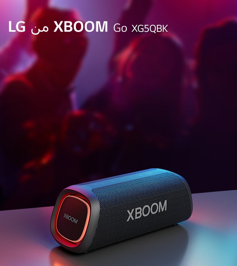 مكبر الصوت XBOOM Go XG5 من LG موضوع على طاولة معدنية ومضبوط على وضع الإضاءة البرتقالية. أشخاص يستمتعون بالموسيقى من خلف الطاولة.
