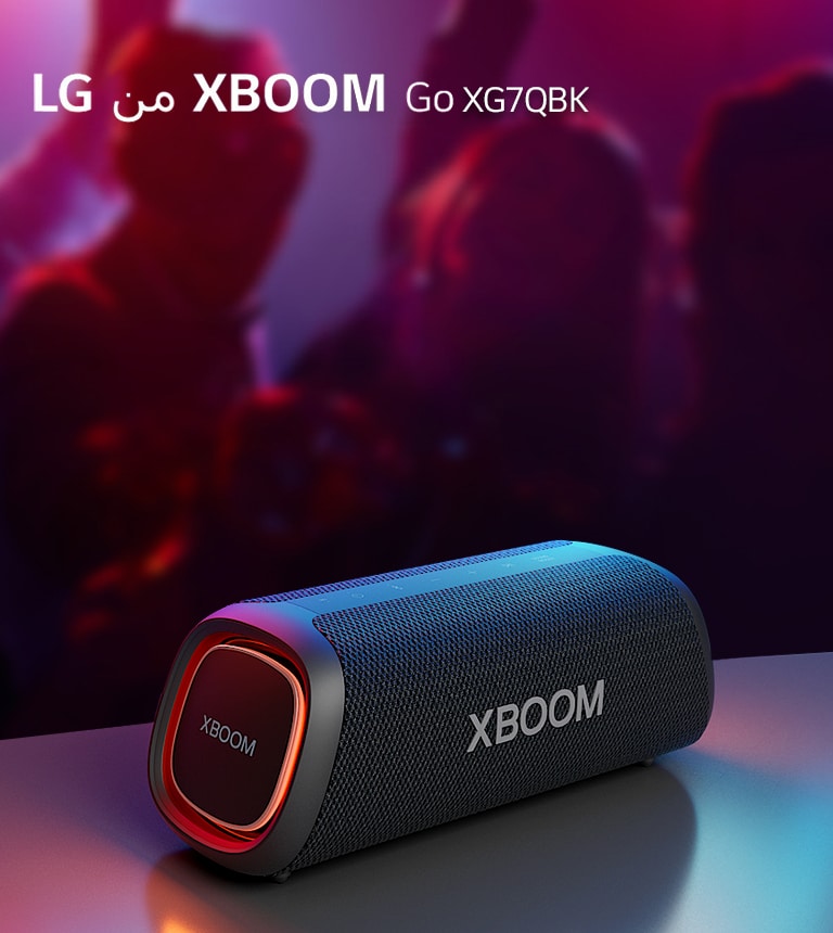 مكبر الصوت XBOOM Go XG5 من LG موضوع على طاولة معدنية ومضبوط على وضع الإضاءة البرتقالية. أشخاص يستمتعون بالموسيقى من خلف الطاولة.