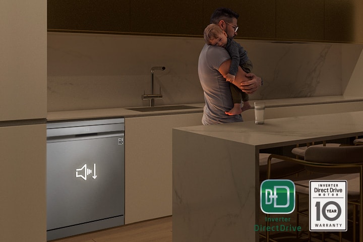رجل يحمل طفلاً نائمًا أثناء تشغيل غسالة الأطباق الهادئة في الخلفية