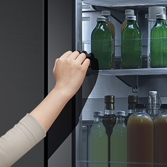 صورة أمامية لثلاجة InstaView ذات الزجاج الأسود مع إضاءة داخلية. أيدي تنقر على شاشة InstaView.