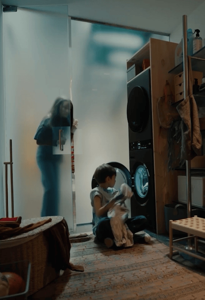 تستخدم أم وابنها غسالة LG AI معًا، ويديران المقبض لتفعيل وظيفة AI Wash. يظهر رجل يستخدم كمبيوتر LG gram في نفس المشهد.