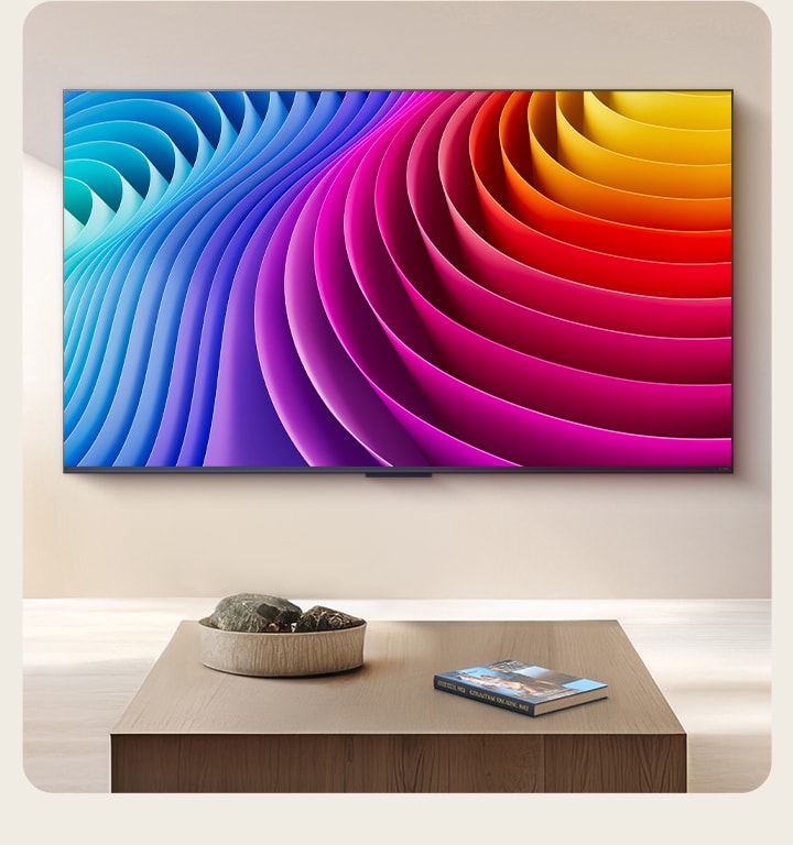 LG QNED TV is mounted on the wall of a beautiful, premium living room. On the TV is an abstract image that features a gradient of different hues that showcases how Dynamic QNED Color Pro can render a wide range of colors. 
