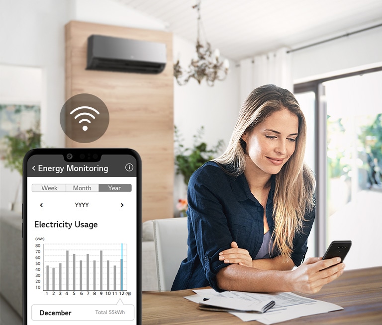 Woman sitting at table checks electricity usage on smartphone app while air conditioner is on, in bright living room.