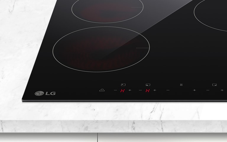 LG induction cooktop with four cooking zones and touch controls, placed on a white marble countertop.