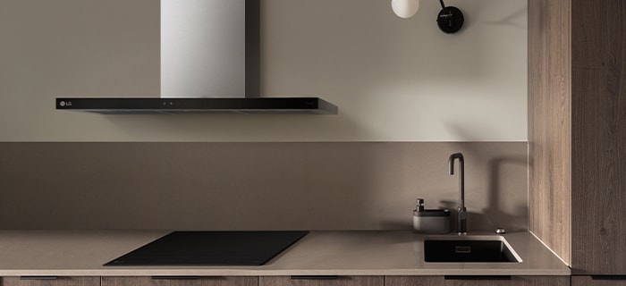  Modern kitchen with an LG range hood centered above a black cooktop, and a sink with a faucet on the right.