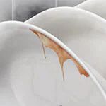  Dirty white plates with brown food residue on the top rack of a dishwasher.