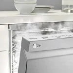 LG stainless steel dishwasher beneath a white kitchen counter, releasing steam while operating.