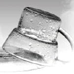  Two clear glass mugs stacked upside down, covered with water droplets, on a reflective white surface.