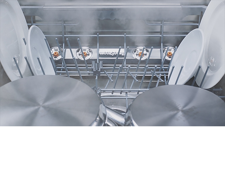Footage of close-up view of various kinds of dishes being steam-washed inside dishwasher.