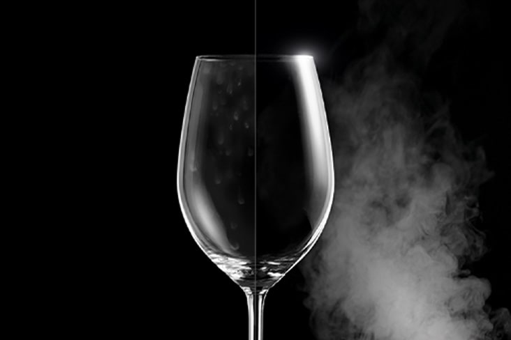 A wine glass with water spots on one side, and clear and pristine on the other after steam washing.	