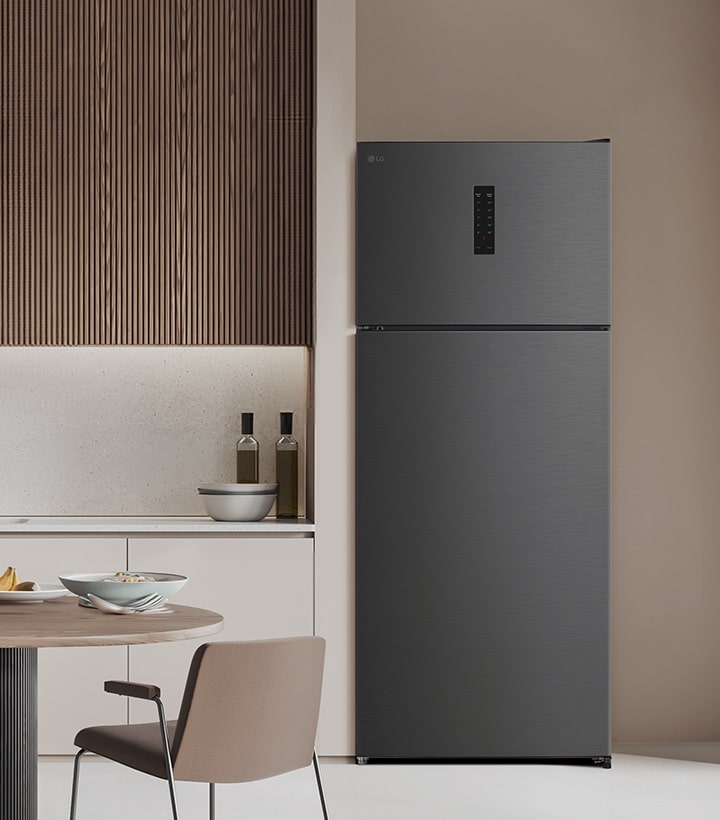 Top freezer refrigerator placed in a modern kitchen with wooden wall panels and a clean table setting	