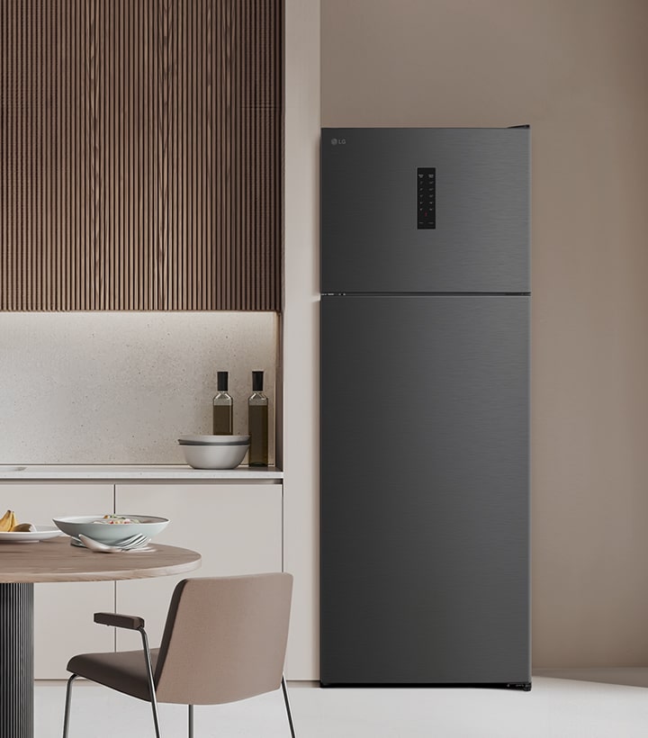 Top freezer refrigerator placed in a modern kitchen with wooden wall panels and a clean table setting