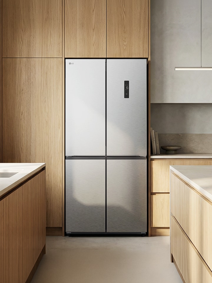 Modern kitchen interior with a silver built-in refrigerator, wood cabinets, and a kitchen island with stools.