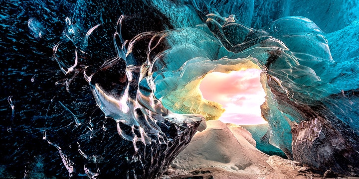Perspectiva desde el interior de una cueva, mirando hacia la entrada. La cueva tiene un aspecto surrealista, con formaciones rocosas y cristalinas muy detalladas. La escena destaca la calidad de imagen sin pérdidas visuales de los televisores True Wireless de LG.