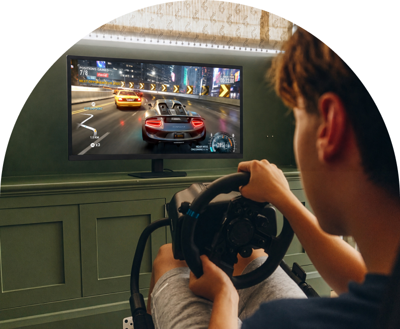 Estudiante disfrutando de un juego de carreras en un monitor gaming LG UltraGear con un volante.