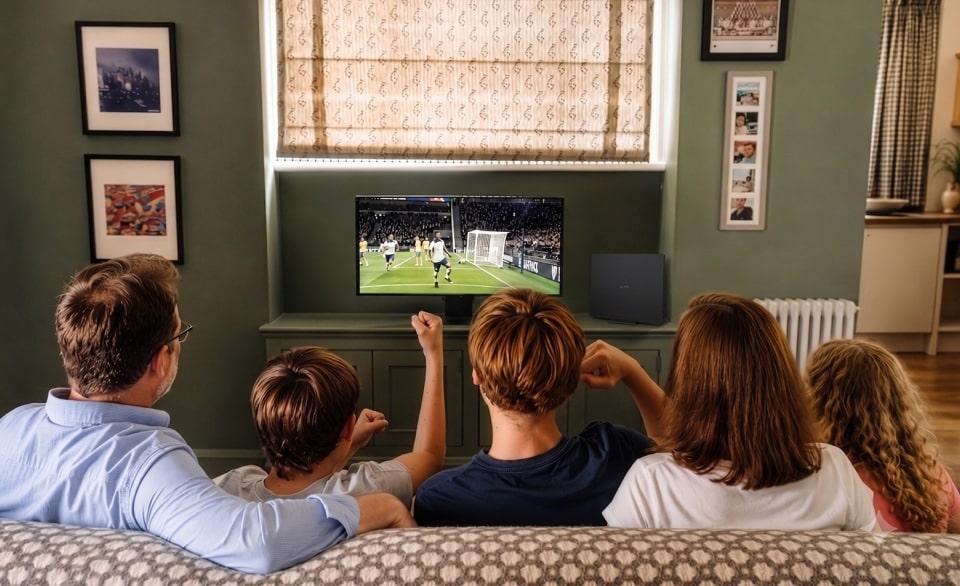Vista trasera de la familia Ferguson reunida viendo un partido de fútbol.