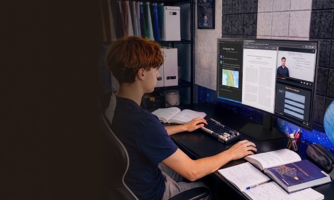 Un estudiante sentado en un escritorio estudiando con un monitor de computadora grande que muestra varias ventanas abiertas, incluyendo notas educativas, una conferencia en video y materiales de aprendizaje dinámicos. Libros de texto, un cuaderno con escritura a mano y suministros de estudio están ordenados en el escritorio a su alrededor.