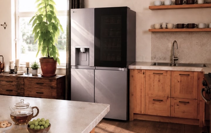 Un elegante frigorífico negro mate LG en una cocina rústica bien iluminada con armarios de madera.