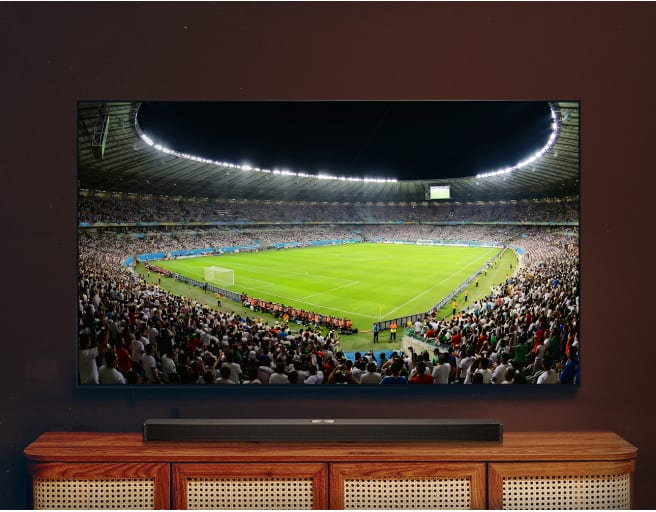 Fernseher zeigt eine weite Ansicht eines Fußballstadions während eines Spiels