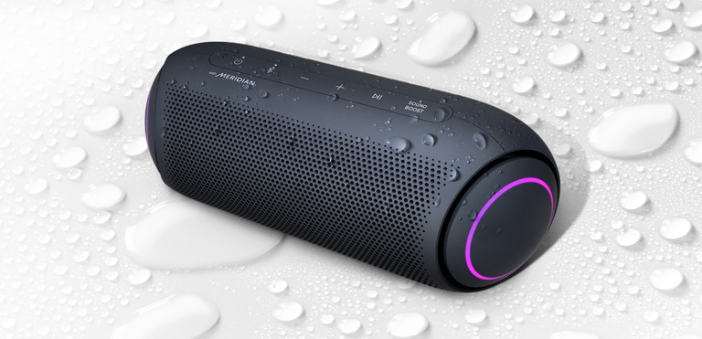 Sobre un fondo blanco, el LG XBOOM Go está boca arriba hacia la izquierda. Hay gotas de agua encima y debajo del LG XBOOM Go.