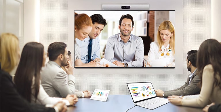 Se está llevando a cabo una videoconferencia mientras se examina a las personas en los carteles instalados en la pared.