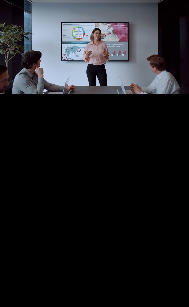 La gente se reúne conectando un dispositivo USB a un ordenador portátil y compartiendo una pantalla con una gran señalización en la pared.