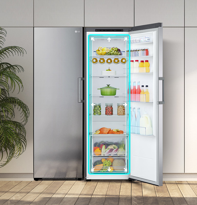Nevera LG abierta con frutas, verduras y bebidas en una cocina moderna, junto a una planta y flores en una mesa.