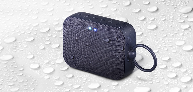 "Sobre un fondo blanco, el LG XBOOM Go PN1 está boca arriba hacia la izquierda.  Hay gotas de agua encima y debajo del LG XBOOM Go PN1."