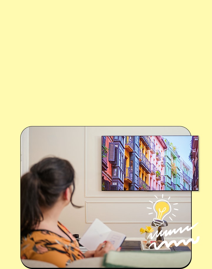 La mujer está viendo televisión con un cuaderno.	