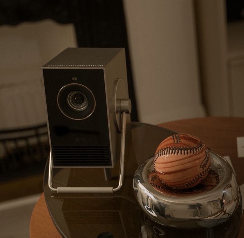 Proyector LG CineBeam Q colocado sobre una mesa de cristal junto al béisbol