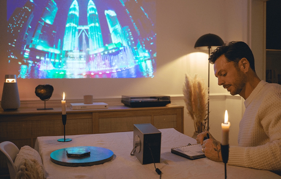 Proyector LG CineBeam Q colocado sobre una mesa de cristal con una pelota de béisbol y gafas.
