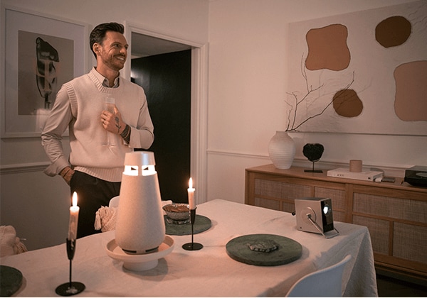 Nick sonriendo, con el proyector LG CineBeam Q y el altavoz LG XBOOM colocados sobre la mesa.