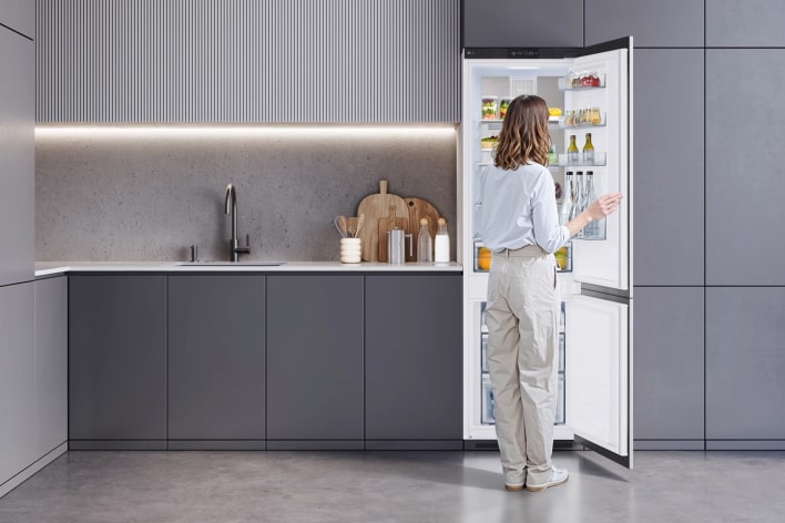 Mostrando cómo se puede colocar la puerta del frigorífico integrable LG con congelador inferior.	