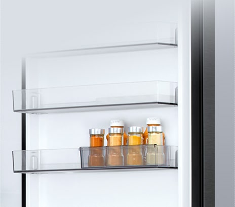 Vista interior de un congelador inferior LG con una cesta deslizante transparente que contiene seis botellas pequeñas de salsa.    