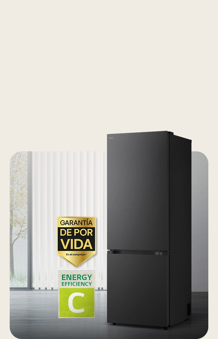 Vista frontal de un congelador inferior LG negro mate, colocado en una habitación luminosa con persianas verticales. A continuación se muestran la garantía de 10 años del compresor y los iconos de eficiencia energética A.