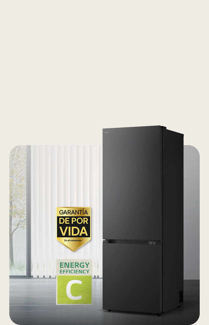 Vista frontal de un congelador inferior LG negro mate, colocado en una habitación luminosa con persianas verticales. A continuación se muestran la garantía de 10 años del compresor y los iconos de eficiencia energética A.